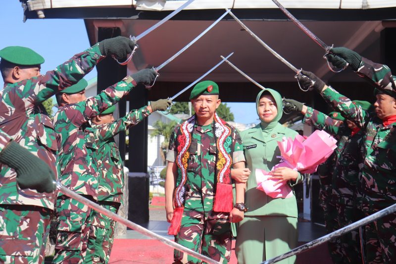 Letkol Inf Raden Herman Sasmita bersama Ketua Persit Kartika Chandra Kirana Cabang XXII Kodim 0106/Aceh Tengah, Ny. Gustin Raden Herman Sasmita, melintasi gerbang kehormatan Pedang Pora saat prosesi pelepasan di Makodim 0106/Aceh Tengah, diiringi penghormatan prajurit, Kamis (23/7/2026).(Dok:Ist)