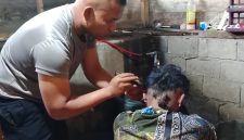 Aipda Candra Sugara, SH saat memangkas rambut pasien penderita gangguan saraf, Minggu (26/7/2026), di wilayah Kecamatan Bandar.(Dok: Rahmat Ramadhan)