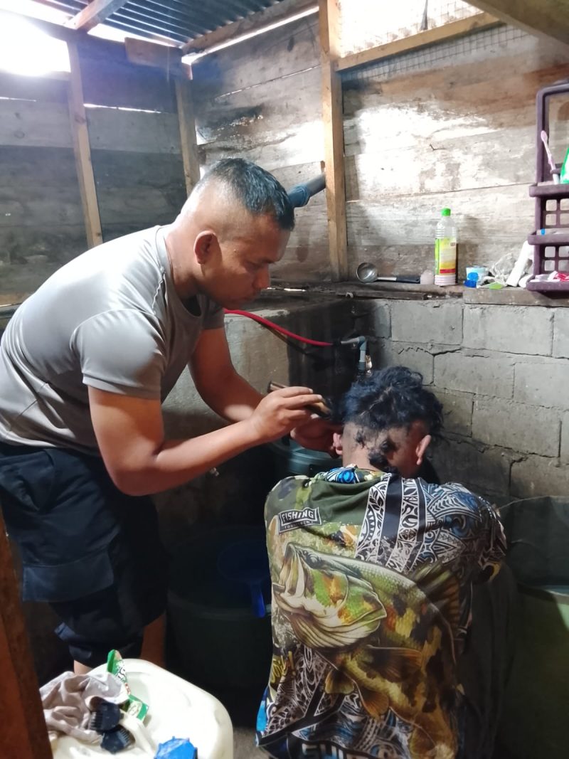 Aipda Candra Sugara, SH saat memangkas rambut pasien penderita gangguan saraf, Minggu (26/7/2026), di wilayah Kecamatan Bandar.(Dok: Rahmat Ramadhan)