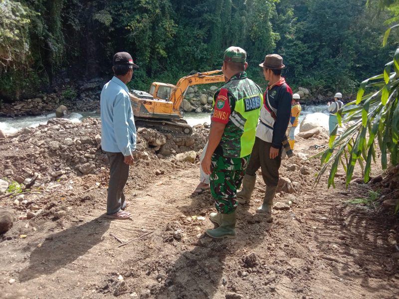 Serda Riswandi, Babinsa Koramil 08/Silih Nara, saat memantau kegiatan normalisasi aliran sungai di Desa Burni Bius Baru, Senin (26/07/2026).(Dok:Ist)