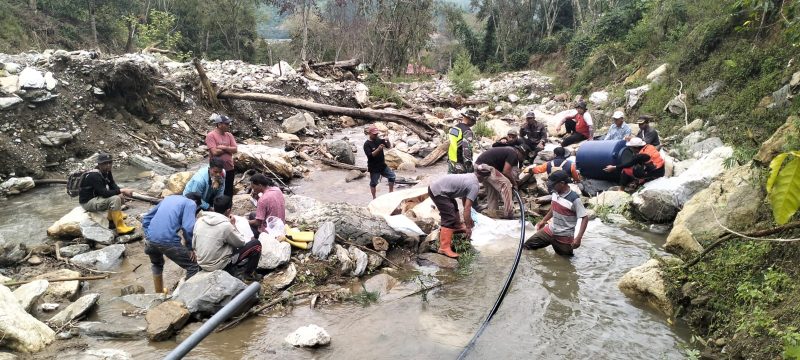 Babinsa Koramil 04/Bintang Serda Amris Gunawan bersama warga Desa Kala Bintang memasang pipa air bersih dari sumber sungai Desa Genuren, Sabtu (1/8/2026). foto.(Dok:Ist)